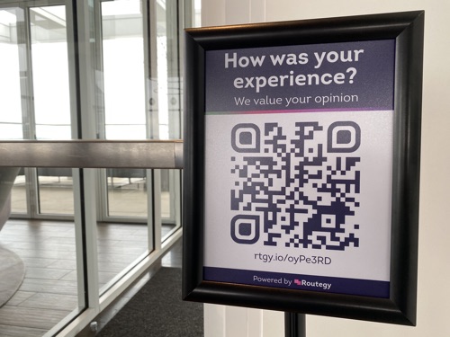 A sign in a doorway asking for customer feedback with a QR code